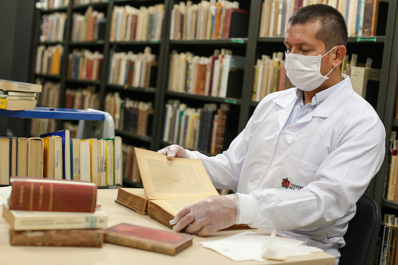 esta es una imagen de un empleado de la biblioteca Karl C Parrish pasando las páginas de un libro antiguo