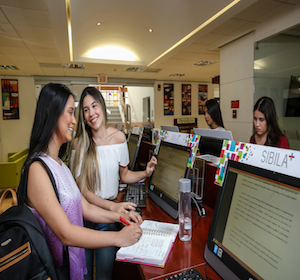 esta es una foto de una estudiantes en los computadores de la biblioteca